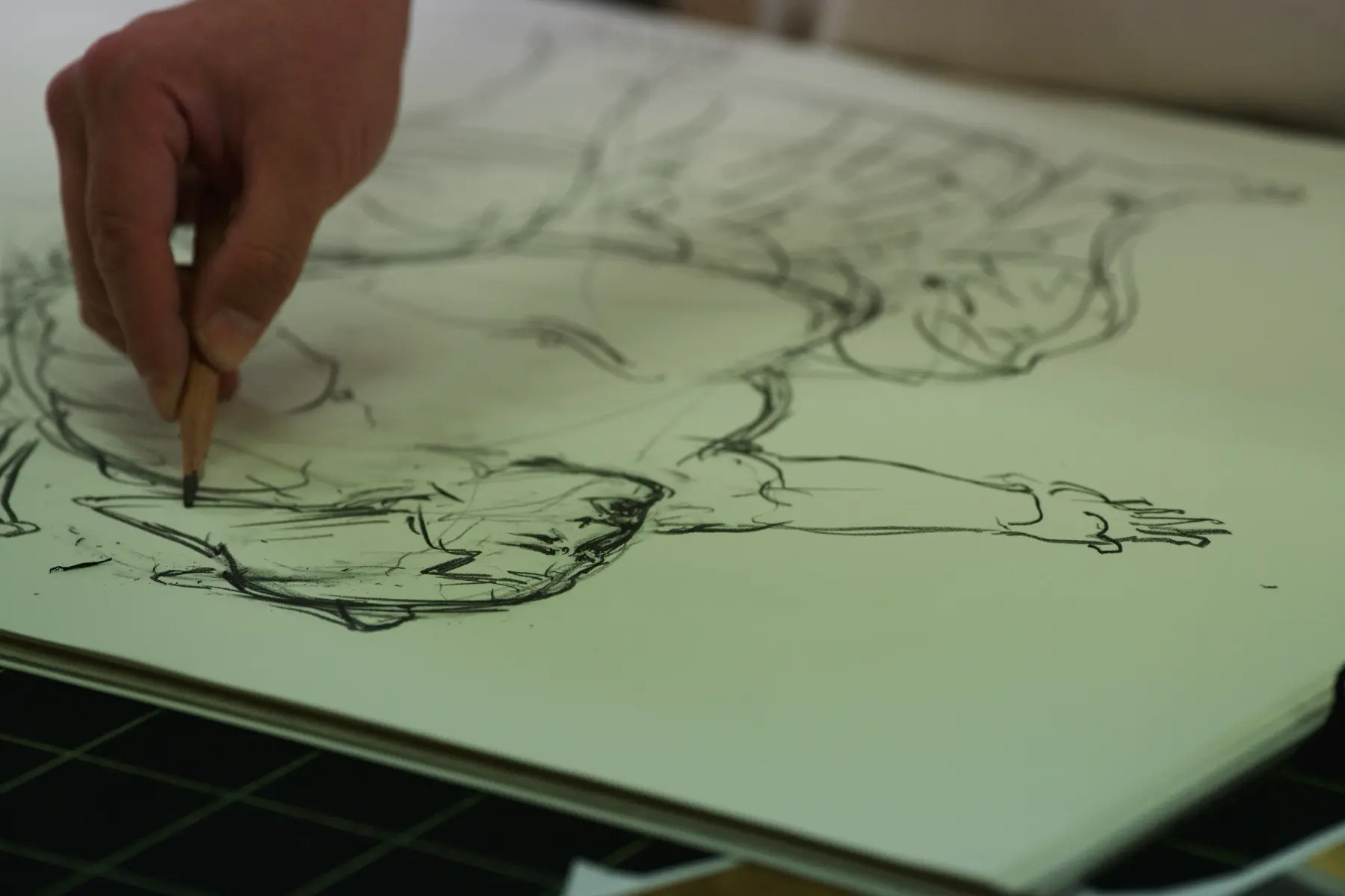力士の全身ラフ画が描かれたスケッチブックと手元
